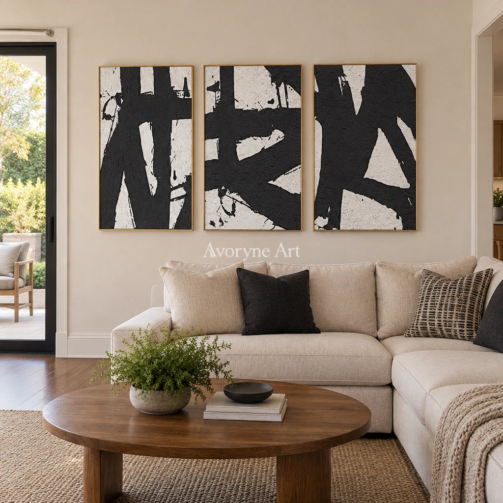 Muted Field black white brushwork triptych with a gold frame hanging in a living room
