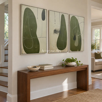 Muted Rhythm olive organic art triptych with a silver frame in an entryway
